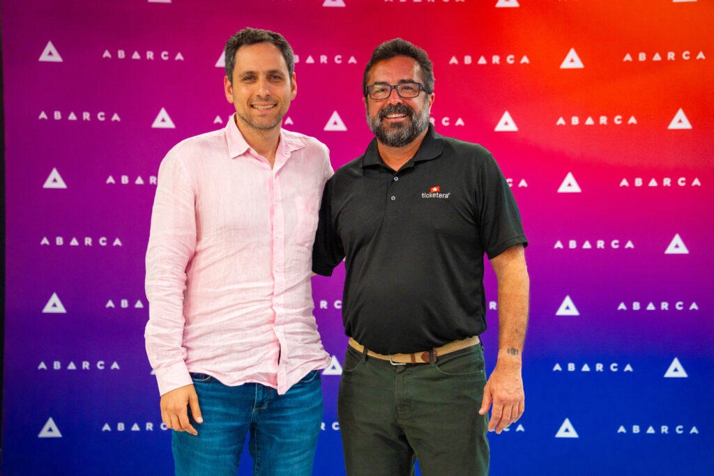Manny Morales and Jason Borschow smiling together in front of an Abarca-branded backdrop during Oasis Connections Season 4, Episode 2.
